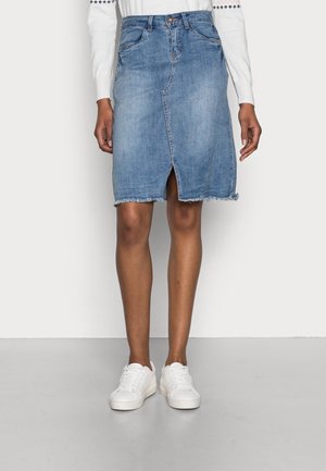 Jeans knielanger Rock in Hellblau, mit ausgefranstem Saum, vorne mit Schlitz und fünf Taschen. Kombiniert mit weißen Sneakers.