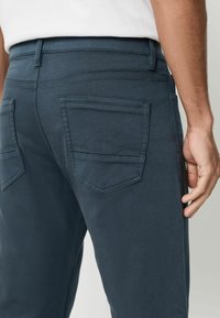 Sötétkék pamutnadrág sima textúrával, két hátsó zsebbel, ferde varrással és karcsú derékrésszel.