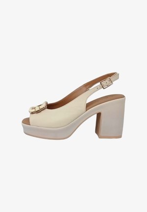 Scarpa slingback in pelle beige con punta larga aperta, dettaglio della fibbia dorata e tacco a piattaforma bianco solido e spesso.