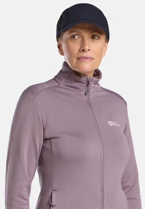 Giacca a zip color lilla chiaro con texture, collo alto e tasche laterali, abbinata a un berretto blu navy. Presenta il logo del marchio sul petto.