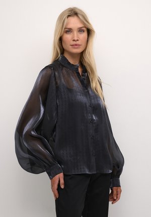 Blusa nera trasparente con un motivo a pied de poule testurizzato, colletto arricciato, maniche lunghe a sbuffo e chiusura con bottoni. Tessuto liscio, leggero.