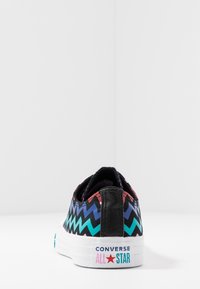 Converse All Star Schuhe mit einem schwarzen Zickzackmuster in Pink, Türkis und Blau, einer weißen Gummisohle und einem schwarzen Absatz.