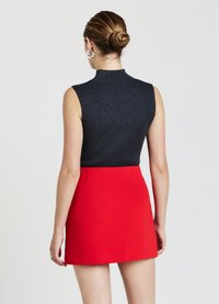 Top senza maniche, a coste di colore blu scuro con colletto alto abbinato a una mini gonna aderente di un vivace rosso. Tessuto liscio con forma strutturata.