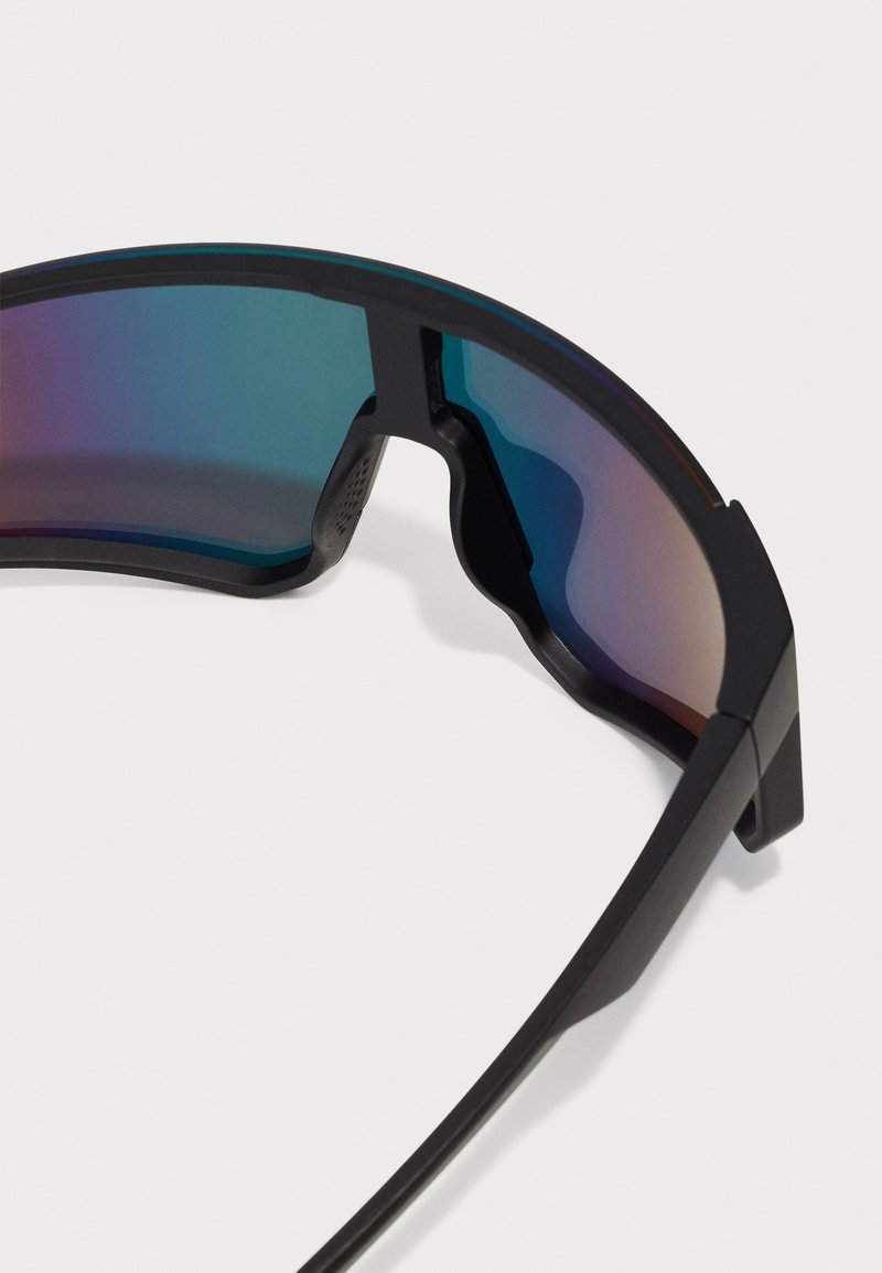 Gafas de sol deportivas negras con un armazón curvado y lentes tintados en degradé, que presentan una textura suave y un diseño angular.