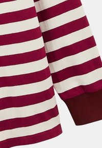 Chemise à rayures marron et crème à manches longues avec des poignets côtelés. Le tissu semble doux avec une texture lisse. Le design présente des rayures horizontales.