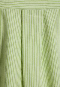 Tessuto a strisce verticali verdi e bianche con un design plissettato, caratterizzato da una superficie liscia e uno spazio uniforme tra le strisce.