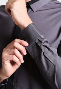 Grijze overhemden met een gladde textuur, gelegen bij de kraag van het shirt, en met knoopmanchetten. De mouw wordt aangepast.