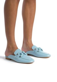 Jasnoniebieskie skórzane mule ze kwadratowym noskiem, ozdobione dekoracyjnym klamrą i płaską drewnianą podeszwą. Elegancki i minimalistyczny design.