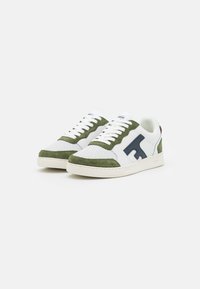 Sneakers bianchi con dettagli in suede verde e logo blu navy. Presentano pannelli perforati e lacci bianchi, su una suola in gomma crema.