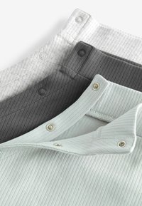 Tre magliette a righe in grigio chiaro, carbone e verde menta. Ognuna presenta un colletto con bottoni a pressione e un tessuto testurizzato.