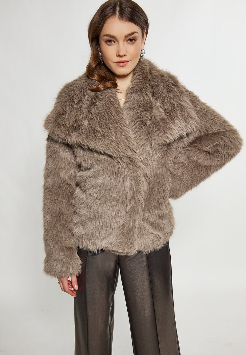 Brun faux fur jakke med bred krave, lange ærmer og en afslappet pasform. Har en blød tekstur og er parret med metalliske bukser.