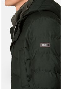 Ciemnozielona kurtka puchowa z kapturem, o miękkiej fakturze, pikowanym wzorze, bocznych kieszeniach i naszywce marki na lewym rękawie.