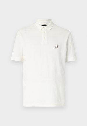 Vit pikétröja i bomull, med en krage med två knappar, korta ärmar och en liten broderad logotyp i brunt på vänster bröst.