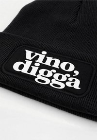 Black knit beanie featuring a wide cuff and a rectangular patch with white text reading "vino, digga" in bold font.