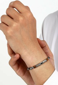 Zilverkleurige metalen armband met cilindrische en ronde kralen, waarvan sommige een diepe bruine kleur hebben. De textuur is glad met metalen accenten.