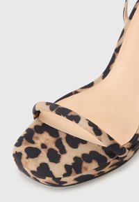 Sandale cu toc înalt, cu imprimeu de leopard, cu o talpă interioară netedă de culoare nud, curele subțiri peste degete și o formă rotunjită a vârfului. Talpă exterioară din cauciuc negru.