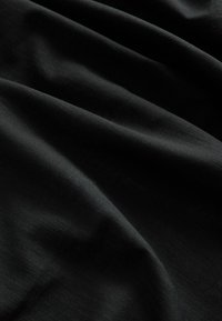 Čierna tkanina s jemnými, plynulými záhybmi a jemnou textúrou, vytvárajúca hladký a elegantný závesný efekt.