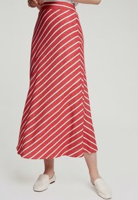 Jupe maxi à rayures rouges et blanches en tissu léger, avec une coupe évasée et une taille ajustée, longueur genoux, avec une texture lisse.