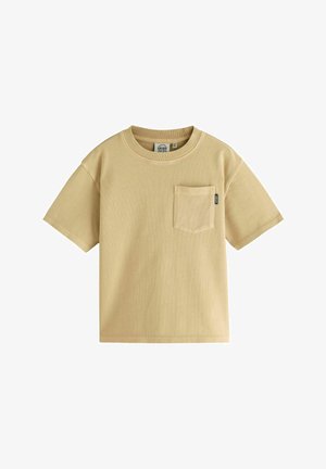 Camiseta de manga corta color beige, hecha de algodón, con un bolsillo en la parte frontal y un cuello redondo con una sutil textura acanalada.