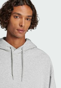 Felpa grigia chiara con una vestibilità comoda, cappuccio con coulisse e una texture sottile. Tessuto liscio dal design casual, che mette in mostra uno stile minimalista.