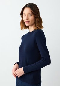 Granatowy sweter robiony na drutach z długimi rękawami i okrągłym dekoltem. ściągacze przy mankietach i dole, dopasowany krój o gładkiej, miękkiej fakturze.