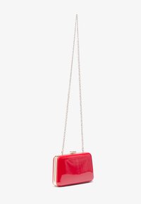 Pochette en cuir verni rouge avec matériel doré, de forme rectangulaire et dotée d'une chaîne. Texture lisse avec des détails de fermoir.