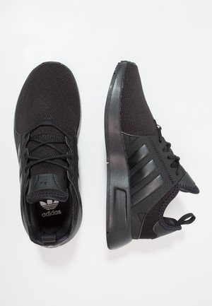 Para czarnych sneakersów Adidas z siateczkowymi cholewkami, trzema bocznymi paskami, sznurowanym fasonem i wyściełanymi podeszwami na białym tle.