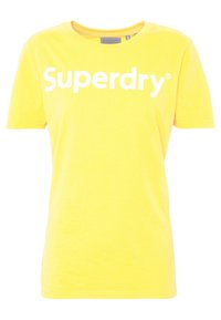 Camiseta de algodón amarilla con cuello redondo y mangas cortas. Presenta un llamativo texto en blanco "Superdry" impreso en la parte frontal. Textura suave.