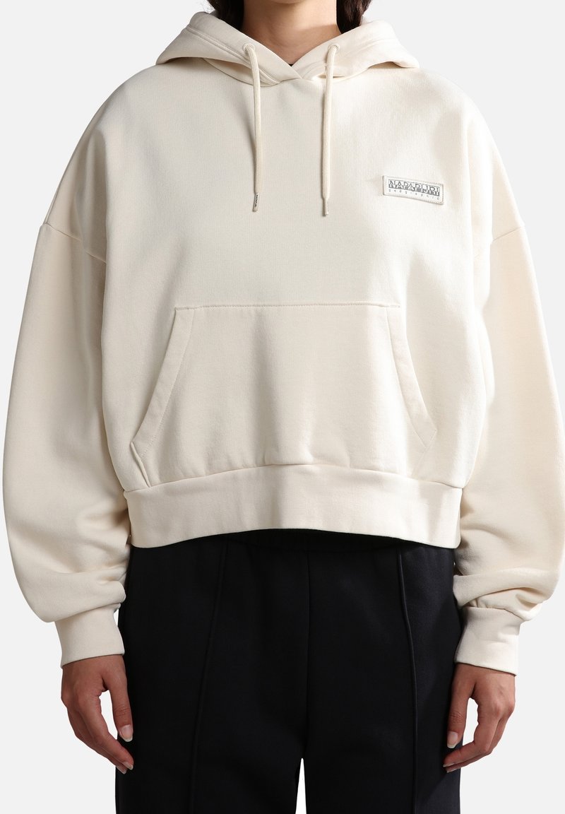 Beige beskuren hoodie med en frampocket, dragsnören och en logopatch. Har breda ärmar och ett mjukt, texturerat tyg.