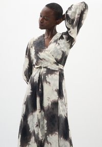 Rochie lunga, dintr-un material lejer, cu un model de nori alb-negru și dungi verticale. Mâneci lungi și un cordon la talie.
