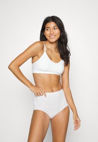 White bra and high-waisted brief set, made from smooth fabric. Features narrow straps and a seamless design. Soft texture and neutral color.