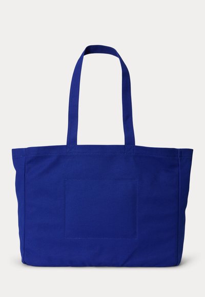 Μεγάλη τσάντα ώμου από μπλε ύφασμα με δύο λαβές και ένα μικρό μπροστινό τσεπάκι, ραμμένη πάνω σε απλό λευκό φόντο.