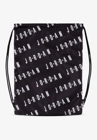 Crna torba s povlačenjem od tkanine s ponavljajućim bijelim logotipom "JORDAN" u različitim orijentacijama. Glatka tekstura s podesivim trakama.