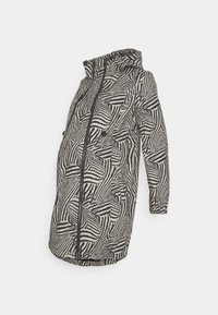 Cappotto per maternità con un motivo a strisce zebra in nero e beige, chiusura con zip, cappuccio e tasche laterali; realizzato in tessuto morbido e testurizzato.