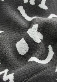 Gray knitted fabric featuring white abstract cat and paw patterns, with a soft, textured appearance and varying thread thickness.