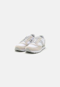 Baskets de course avec un dessus blanc, des accents gris et des superpositions en daim beige. Elles présentent un bout rond, un système de laçage et une semelle extérieure texturée.