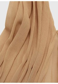 Beige chiffon fabric with soft, flowing folds; lightweight texture; sheer appearance; suitable for layering or draping in garments.