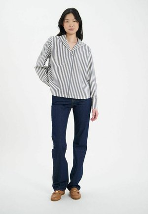 Chemise à rayures bleu clair et blanche, col classique, associée à un jean flare bleu foncé et des chaussures marron. Texture du tissu lisse.