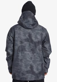 Voděodolná bunda v tmavě šedé barvě s jemným vzorem mraků; obsahuje kapuci a volný střih pro pohodlí.