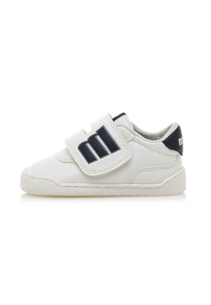 Zapatilla de cuero blanca con suela plana, que cuenta con una correa de velcro y un acento en azul marino en el lateral con un logotipo. Detalle de superficie texturizada presente.