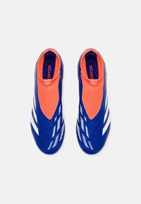 Zapatillas deportivas azules con un diseño de tipo slip-on, que presentan una superficie texturizada, un forro de tela naranja y franjas de acento blancas.