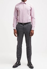 Rot-weiß gestreiftes langärmliges Hemd, graue maßgeschneiderte Hose, schwarze Lederschuhe, glatter Stoff, figurbetontes Design, kontrastierender Gürtel.