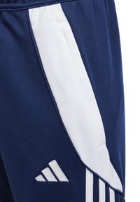 Marineblå idrettsshorts med hvit sidestrekk, laget av teksturert stoff, med en hvit logo detalj nederst til venstre.