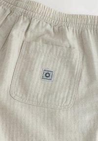 Svijetlosmeđi šorts s uzorkom riblje kosti, elastičnom strukom i stražnjim džepom koji ima kvadratnu oznaku s logotipom.