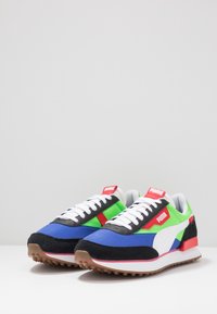 Baskets colorées Puma présentant un mélange de matériaux bleus, verts, noirs et rouges, avec des accents blancs, un tissu texturé et des semelles en caoutchouc.