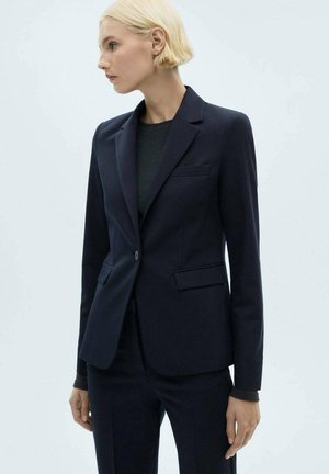 Blazer sartorial blu scuro con rever a punta, due tasche frontali e chiusura con un solo bottone. Realizzato in tessuto morbido con una vestibilità strutturata.