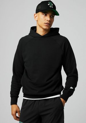 Black hoodie with a front pocket, long sleeves, and a drawstring hood. White logo detail on the left sleeve. Black cap with green accents.