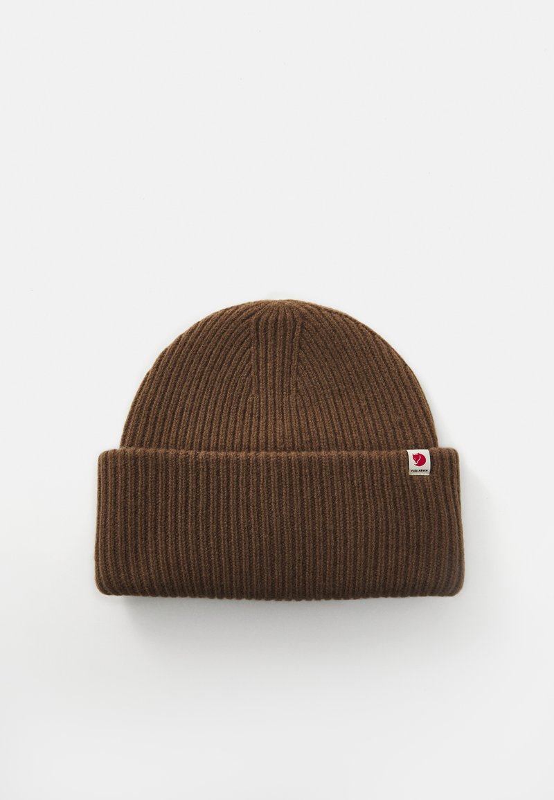 Brown ribbed knit beanie with folded cuff and small red logo tag on side, set against plain white background.