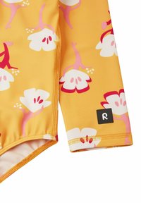 Langärmliger Badeanzug mit einem leuchtend gelben Grundton, der mit pinken und weißen Blumenmustern verziert ist. Enthält ein schwarzes Logo-Label am Ärmel.