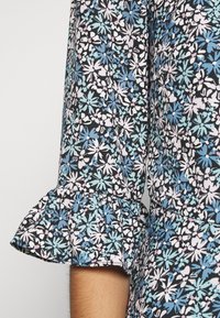 Svart blommig klänning med blå, rosa och vita blommönster. Har volangärmar och lätt tyg med en mjuk textur.